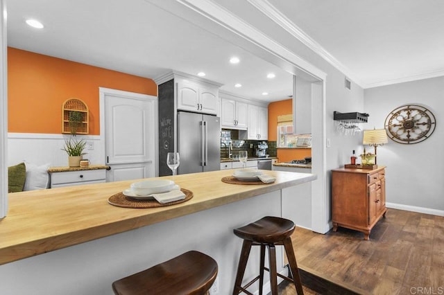 kitchen with wooden counters, dark wood-style floors, a breakfast bar, stainless steel appliances, and recessed lighting