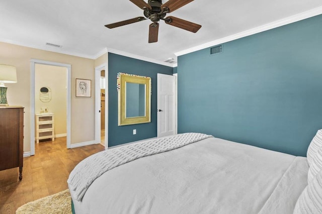 bedroom with baseboards, ornamental molding, wood finished floors, and visible vents