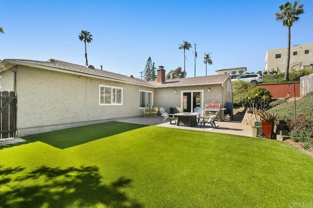 rear view of property featuring fence, a patio, stucco siding, and a yard