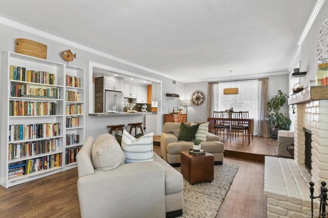 living room with crown molding, visible vents, wood finished floors, and a fireplace