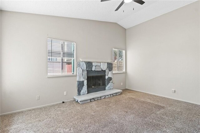 unfurnished living room featuring a ceiling fan, a fireplace, vaulted ceiling, baseboards, and carpet