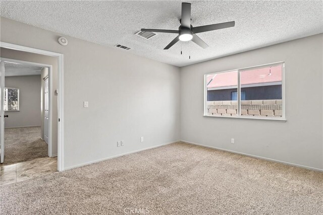 empty room featuring carpet floors, a ceiling fan, a textured ceiling, and visible vents