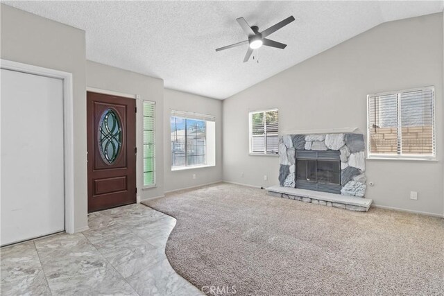 entryway featuring a textured ceiling, a stone fireplace, a ceiling fan, baseboards, and lofted ceiling