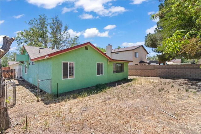 back of property featuring a fenced backyard, stucco siding, and a chimney