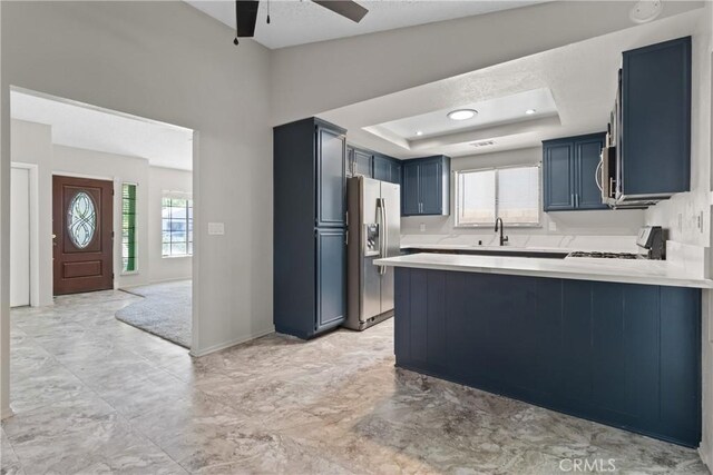 kitchen with ceiling fan, a sink, light countertops, a peninsula, and stainless steel appliances