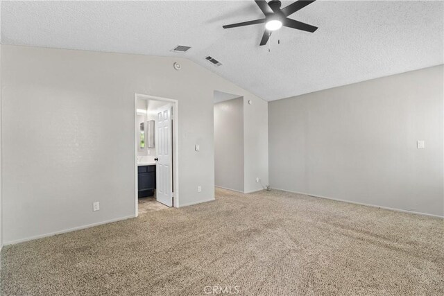 unfurnished room featuring visible vents, lofted ceiling, ceiling fan, light colored carpet, and a textured ceiling