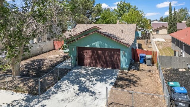 garage featuring fence and concrete driveway