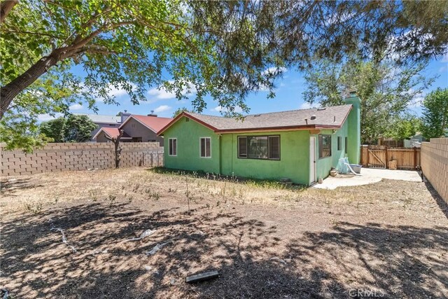 rear view of house featuring a fenced backyard and stucco siding