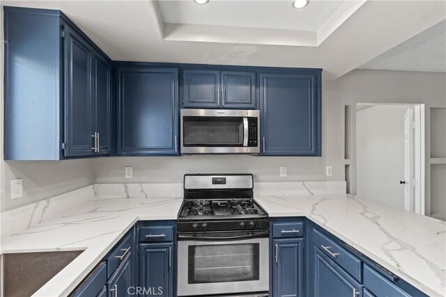 kitchen featuring blue cabinets, stainless steel appliances, light stone counters, a tray ceiling, and recessed lighting