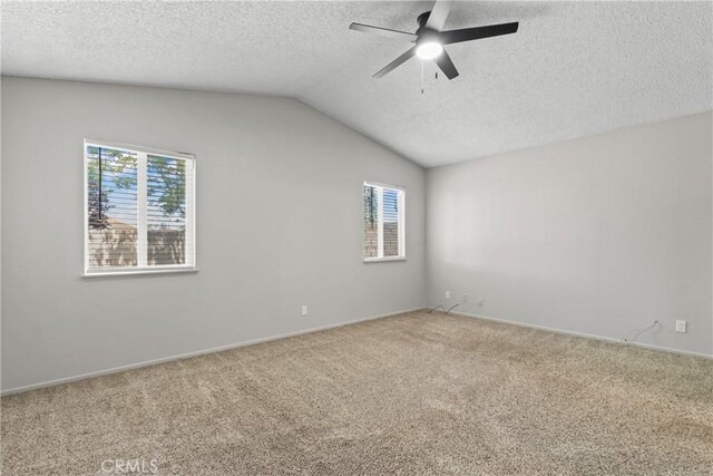 empty room with carpet floors, a ceiling fan, a textured ceiling, and lofted ceiling