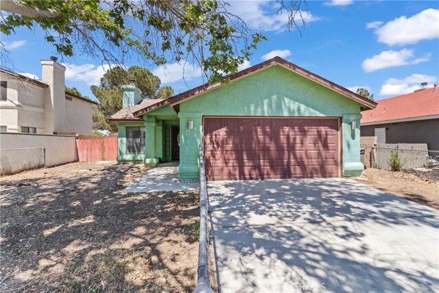 ranch-style home featuring a garage, fence, stucco siding, and driveway