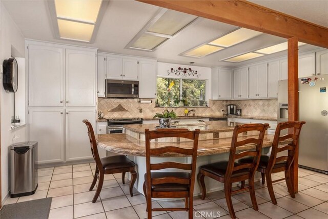36556 Mudge Ranch Rd, Coarsegold, CA 93614 - kitchen featuring decorative backsplash, white cabinets, appliances with stainless steel finishes, and light tile patterned flooring