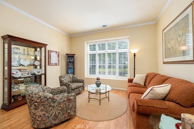 living area with light wood-type flooring, crown molding, and visible vents