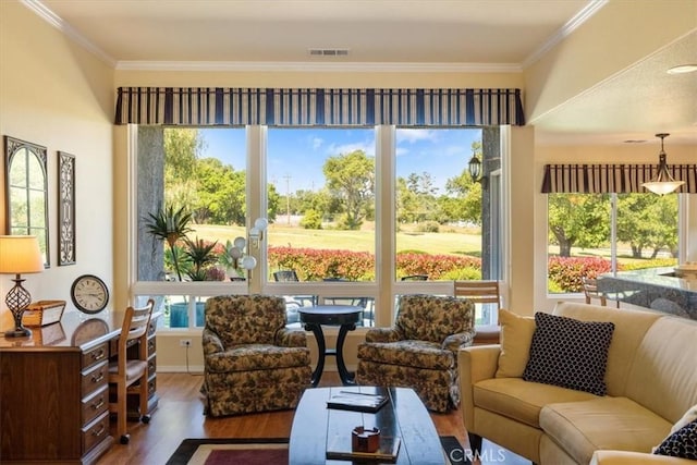 sunroom with visible vents, ornamental molding, wood finished floors, and a wealth of natural light