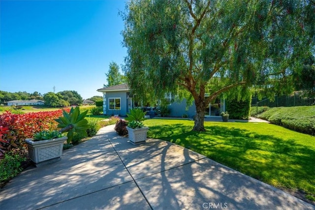 view of home's community with a patio area, fence, and a yard