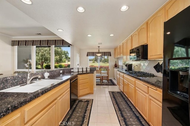 kitchen featuring light brown cabinetry, backsplash, a sink, and black appliances