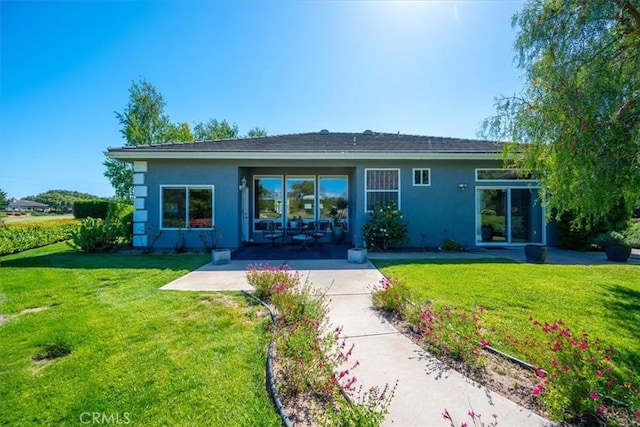 rear view of property featuring a lawn and stucco siding