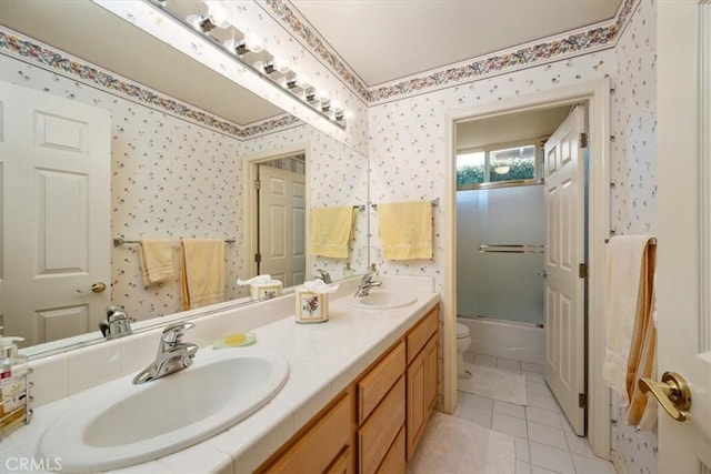 bathroom with toilet, wallpapered walls, and a sink