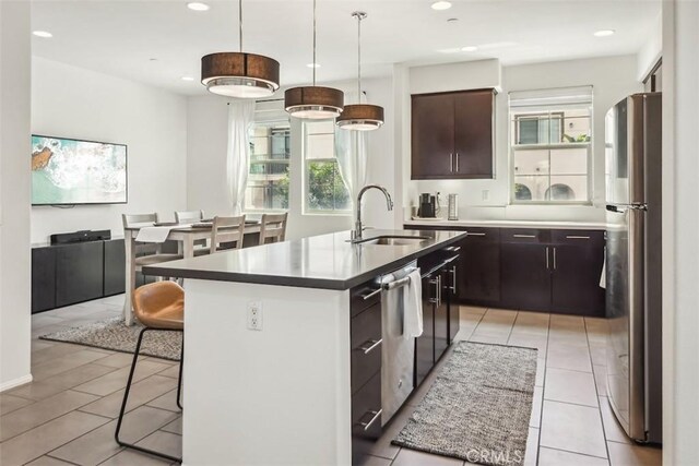 kitchen featuring a kitchen island with sink, a kitchen bar, appliances with stainless steel finishes, a sink, and recessed lighting