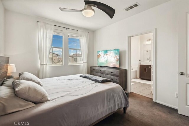 bedroom featuring visible vents, a ceiling fan, ensuite bathroom, and dark colored carpet