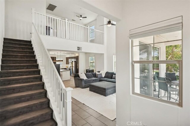 interior space featuring stairway, plenty of natural light, a ceiling fan, and visible vents