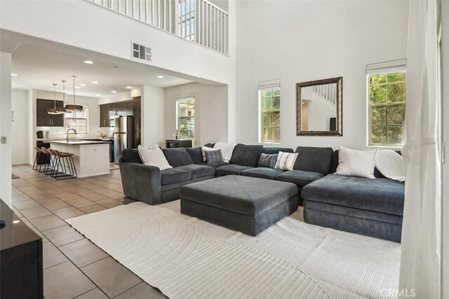 living area featuring recessed lighting, visible vents, light tile patterned floors, and a towering ceiling