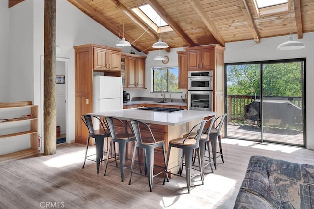 kitchen with a sink, wooden ceiling, a skylight, and light wood-type flooring