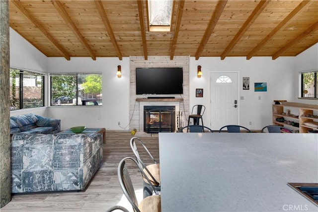 living room with wooden ceiling, vaulted ceiling with beams, a large fireplace, and wood finished floors