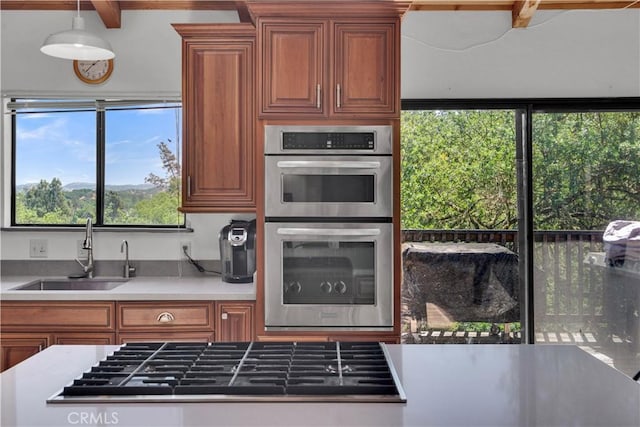 kitchen featuring stainless steel appliances, brown cabinetry, and a sink