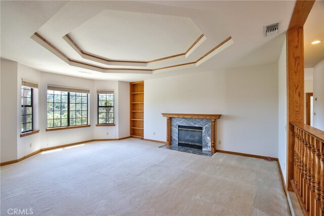 unfurnished living room featuring a tray ceiling, light colored carpet, baseboards, and visible vents