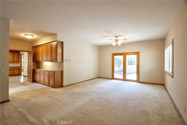 unfurnished living room featuring a ceiling fan, a healthy amount of sunlight, and light carpet