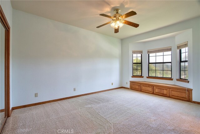 unfurnished room with baseboards, light carpet, and a ceiling fan