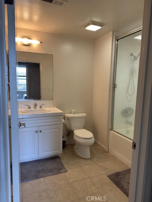bathroom featuring visible vents, tile patterned flooring, vanity, toilet, and enclosed tub / shower combo