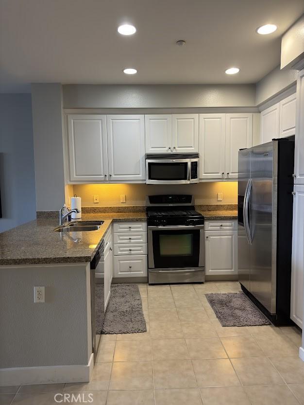 kitchen featuring a peninsula, recessed lighting, white cabinetry, a sink, and appliances with stainless steel finishes