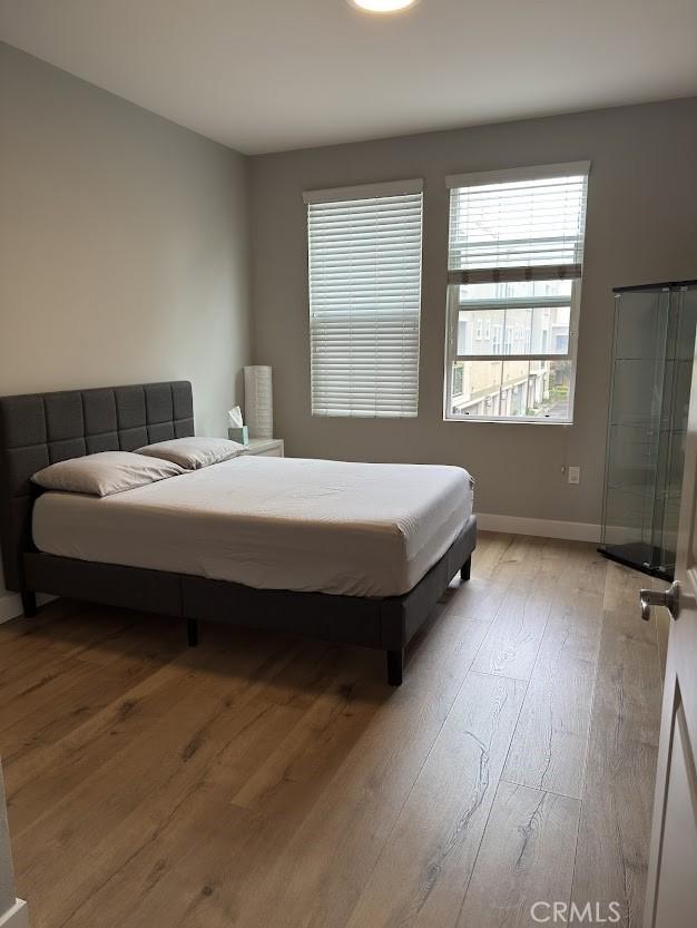 bedroom featuring wood-type flooring and baseboards