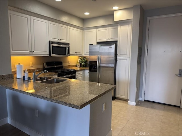kitchen with a peninsula, a sink, appliances with stainless steel finishes, and white cabinetry