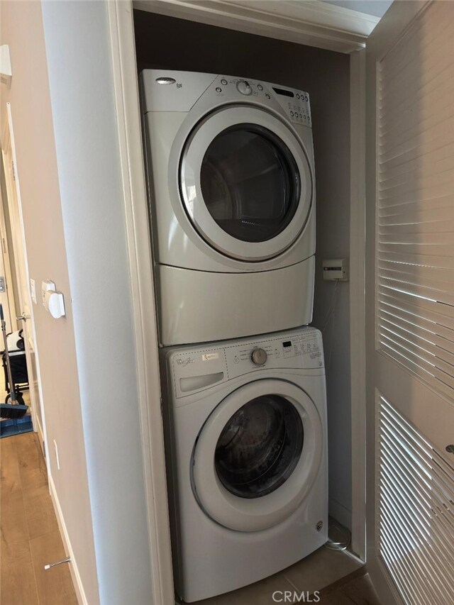 clothes washing area featuring baseboards, laundry area, and stacked washer / dryer