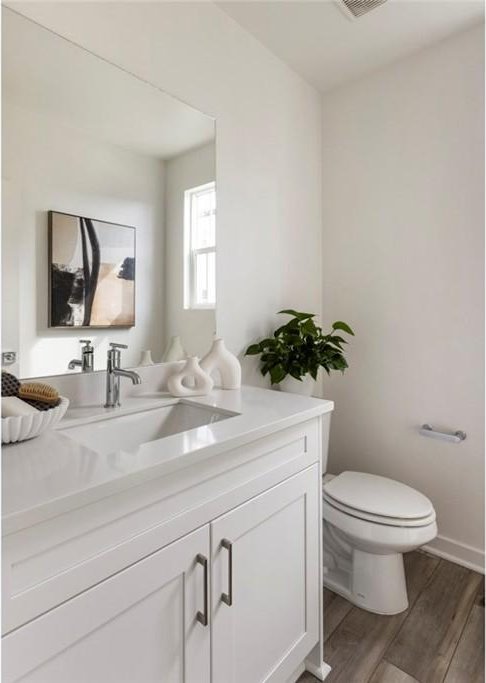 bathroom with toilet, baseboards, wood finished floors, and vanity