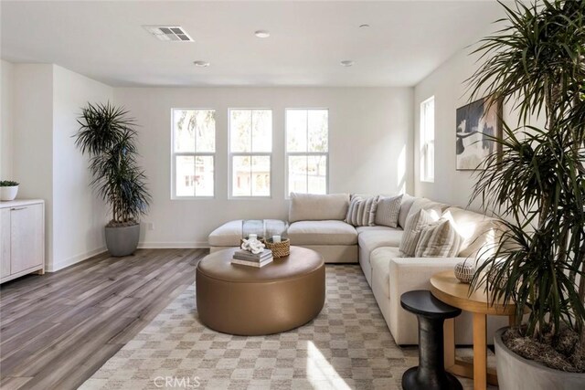 living area with baseboards, light wood-type flooring, and visible vents