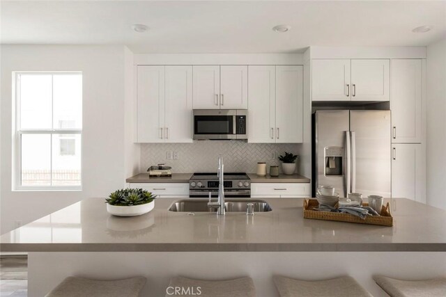 kitchen featuring white cabinetry, appliances with stainless steel finishes, backsplash, and a breakfast bar area