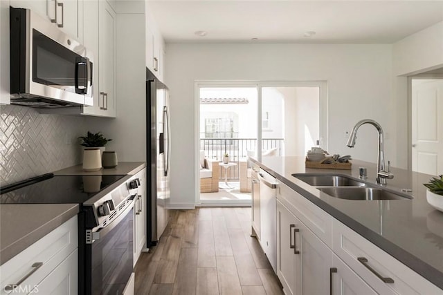 15216 Janine Dr Unit 7, Whittier, CA 90605 - kitchen featuring light wood-style flooring, a sink, white cabinets, backsplash, and appliances with stainless steel finishes