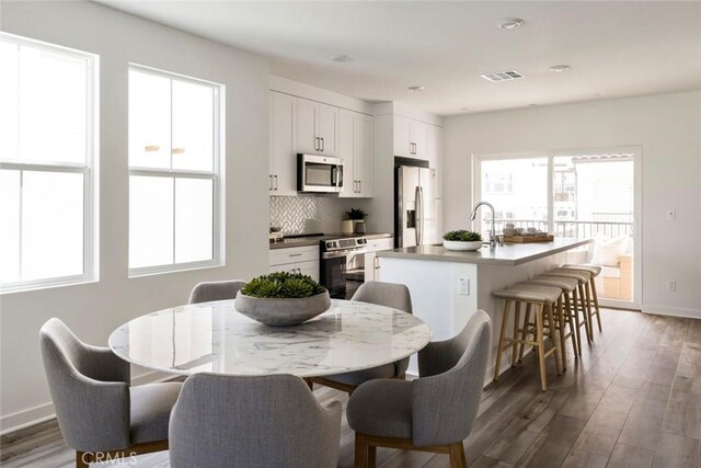 dining area featuring a healthy amount of sunlight, baseboards, wood finished floors, and visible vents