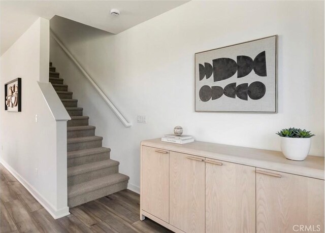 staircase featuring baseboards and wood finished floors