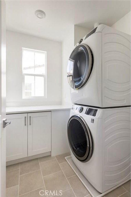 15216 Janine Dr Unit 7, Whittier, CA 90605 - laundry room featuring stacked washer / dryer, light tile patterned flooring, and cabinet space