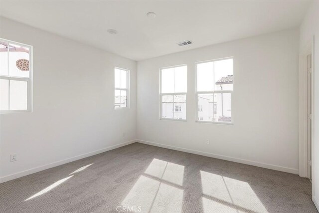 unfurnished room with carpet floors, baseboards, and visible vents