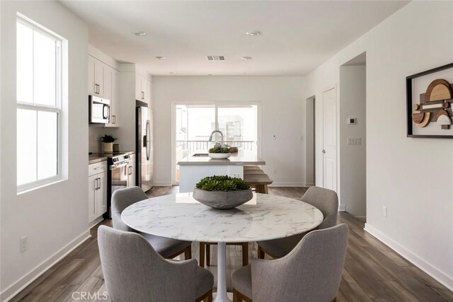 dining space featuring visible vents, dark wood-style flooring, and a wealth of natural light