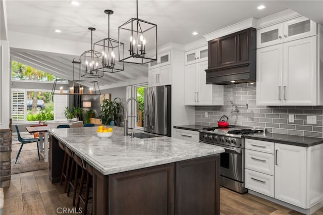 324 W S Ave, Redlands, CA 92373 - kitchen with appliances with stainless steel finishes, a chandelier, dark wood-style flooring, tasteful backsplash, and an island with sink