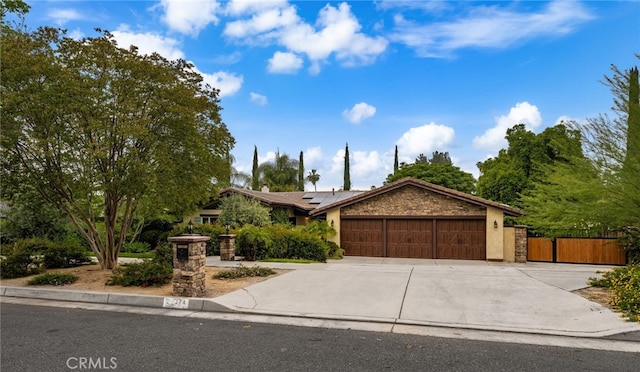 324 W S Ave, Redlands, CA 92373 - view of front facade featuring an attached garage, roof mounted solar panels, concrete driveway, a gate, and stucco siding