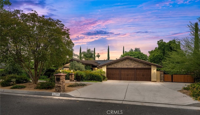 324 W S Ave, Redlands, CA 92373 - view of front of home with a garage, driveway, roof mounted solar panels, stone siding, and a gate