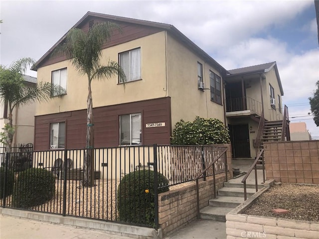 view of side of home with stairway, fence private yard, and stucco siding